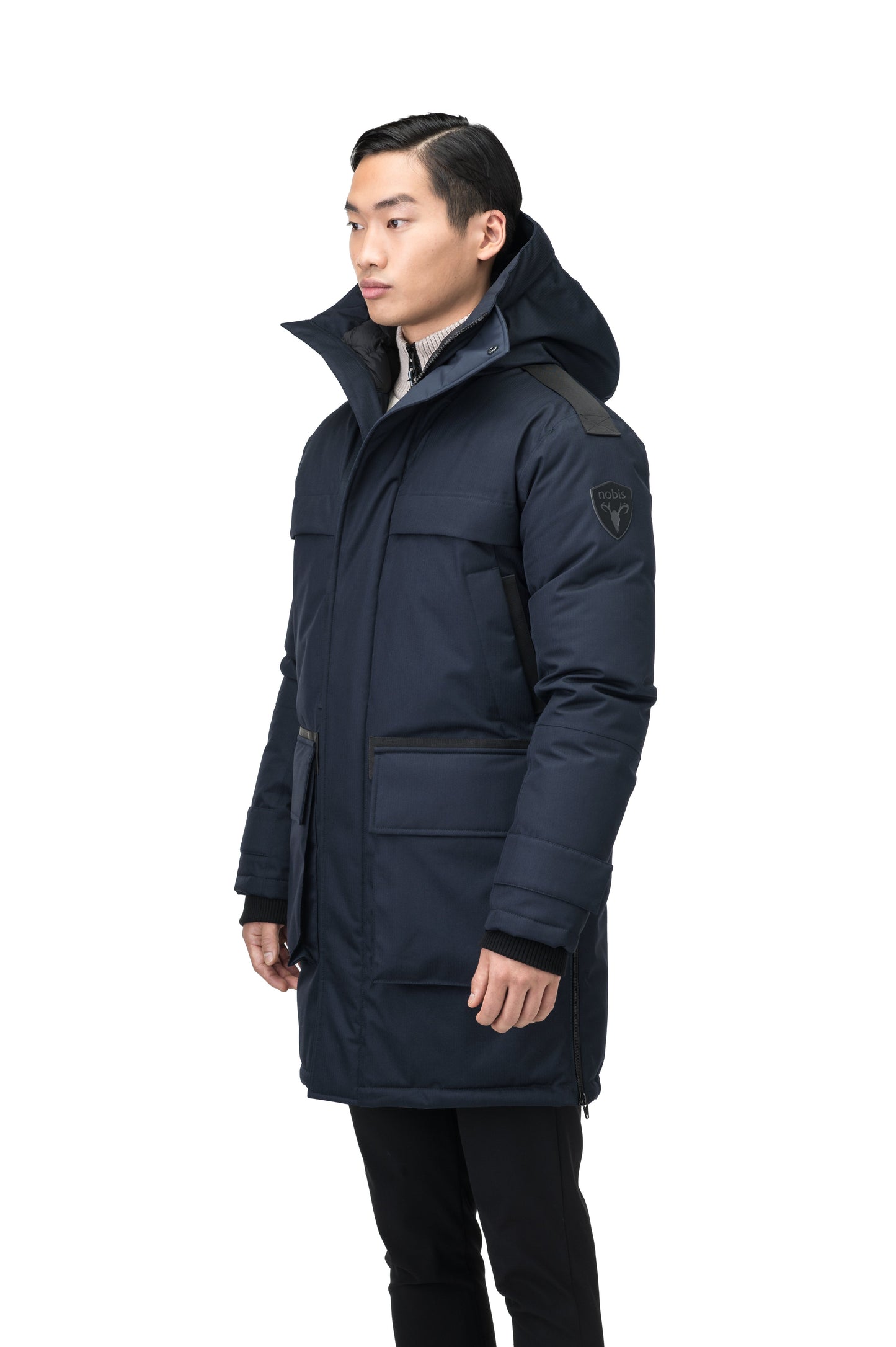 Alum Men's Long Parka in thigh length, Premium Canadian White Duck Down insulation, non-removable hood with removable coyote fur trim, two-way centre front zipper with magnetic closure wind flap, four exterior patch pockets at front, in Navy