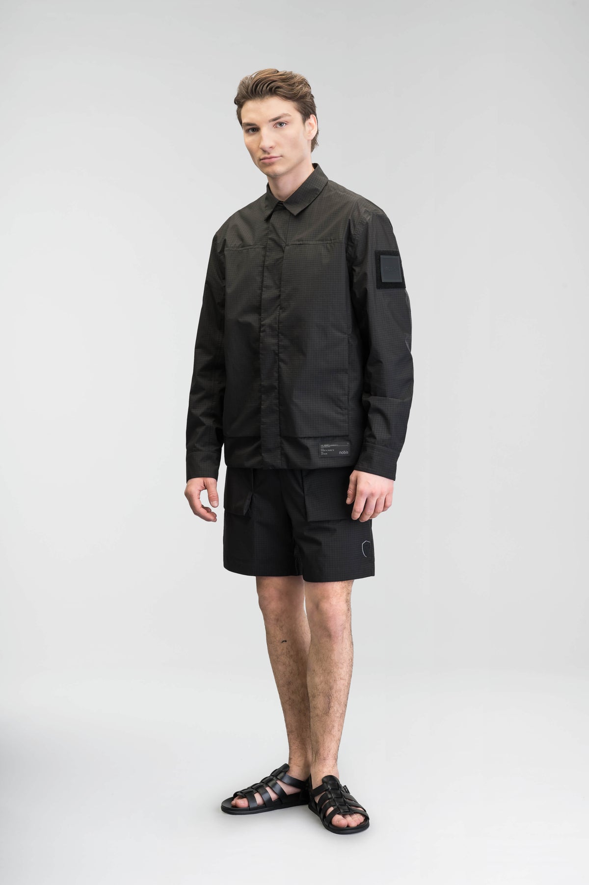 Farson Men's Waterproof Overshirt in Black made from premium recycled polyester ripstop with a DWR coating. Features a concealed snap-button front placket, adjustable snap cuffs, invisible chest zip pocket, dual zippered waist pockets, pit zip ventilation, and seam-sealed construction for enhanced weather protection. Designed in Canada.