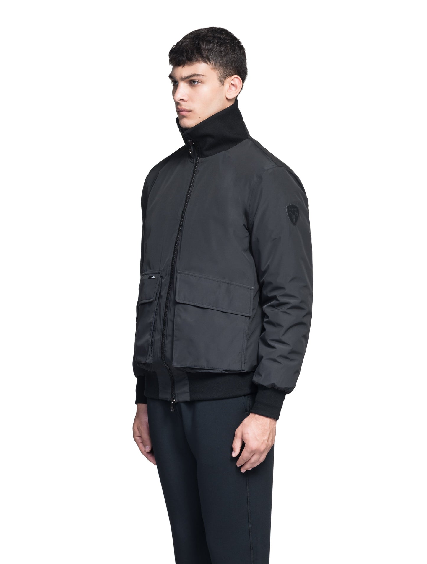 Flint Men's Tailored Rib Collar Jacket in hip length, premium 3-ply Micro Denier fabrication, premium 4-way stretch, water resistant Primaloft Gold Insulation Active +, flap pockets with magnetic closure at waist, side entry pockets at waist, ribbed sleeve cuffs, two-way branded zipper at centre front, box pleat detailing at centre back, large interior zipper pocket, and interior button pocket at left chest, in Black