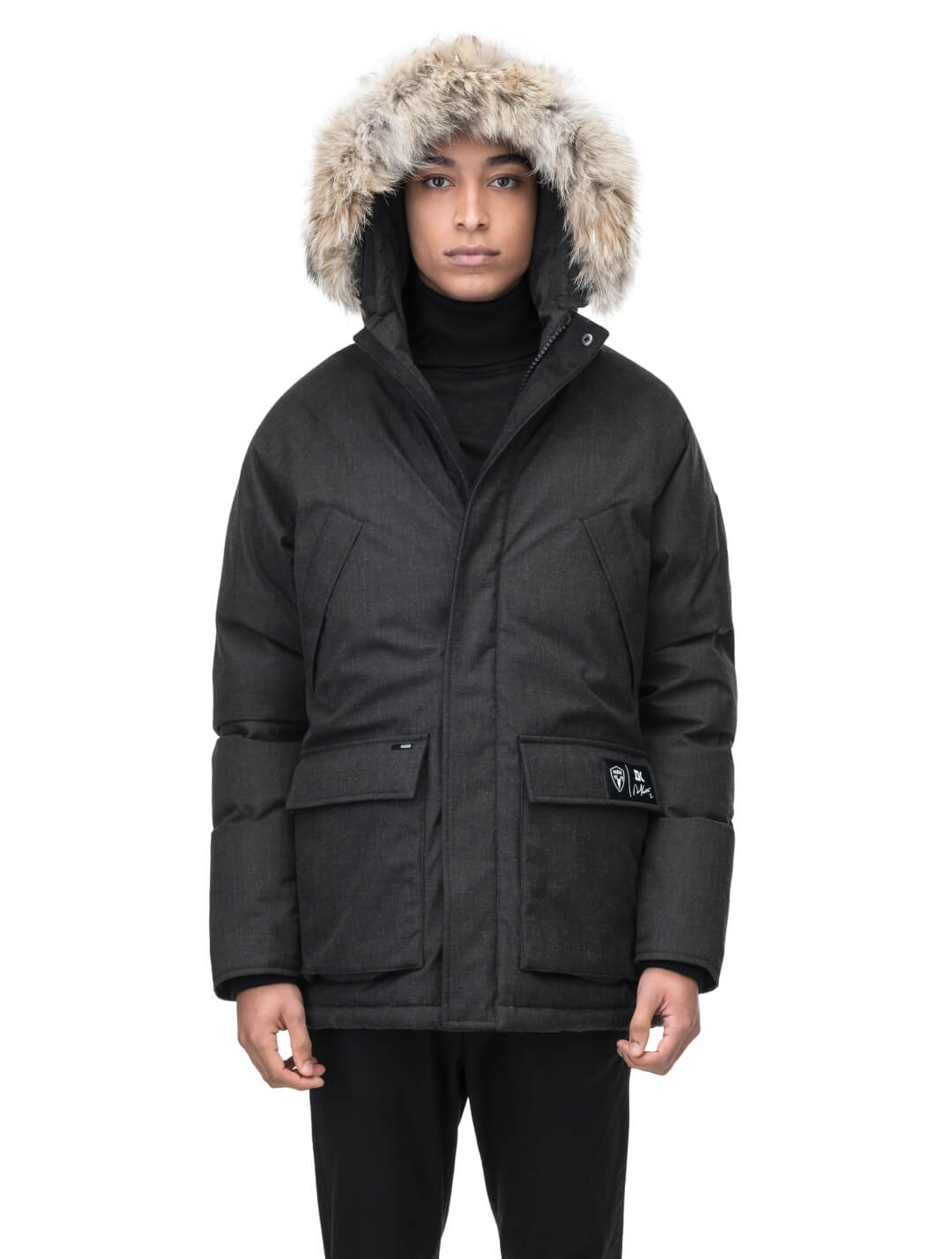 Duncan Keith Heritage Men's Parka in hip length, and features Canadian duck down insulation, non-removable hood with removable coyote fur trim, fleece-lined chest pockets, top and side entry waist pockets, adjustable waist cord, interior zipper pocket, and co-branding with Keith's signature on the left outer waist pocket, in H. Black