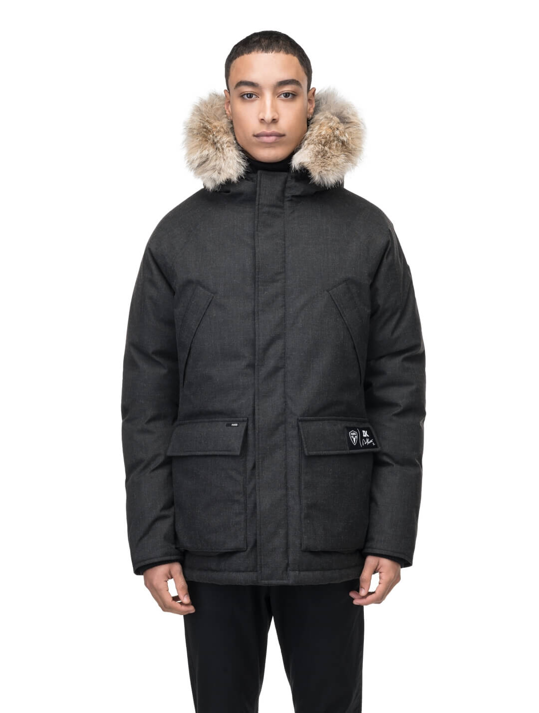 Duncan Keith Heritage Men's Parka in hip length, and features Canadian duck down insulation, non-removable hood with removable coyote fur trim, fleece-lined chest pockets, top and side entry waist pockets, adjustable waist cord, interior zipper pocket, and co-branding with Keith's signature on the left outer waist pocket, in H. Black
