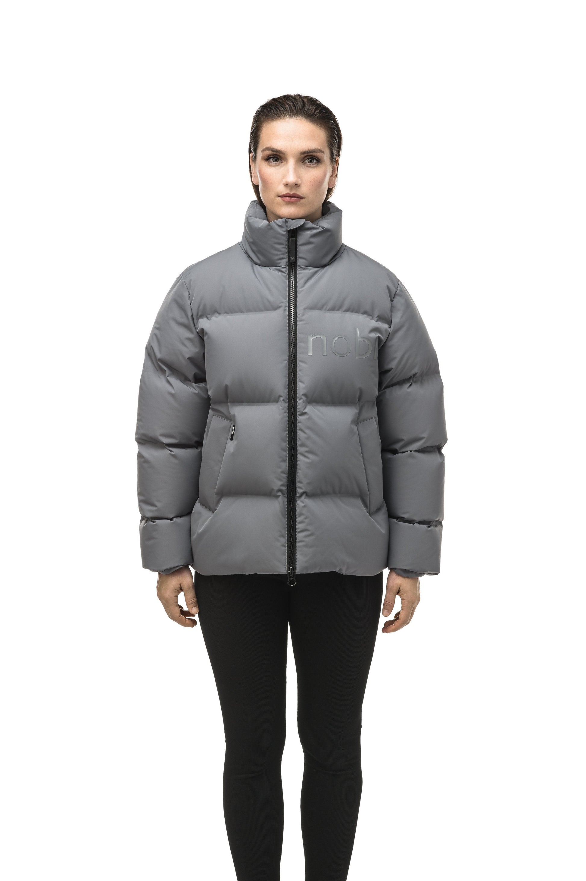 Women's puffer jacket with a minimalist modern design; featuring graphic details like oversized tonal branding, an exposed zipper, and seamless puffer channels to lock in the Premium Canadian Origin White Duck Down in Concrete color