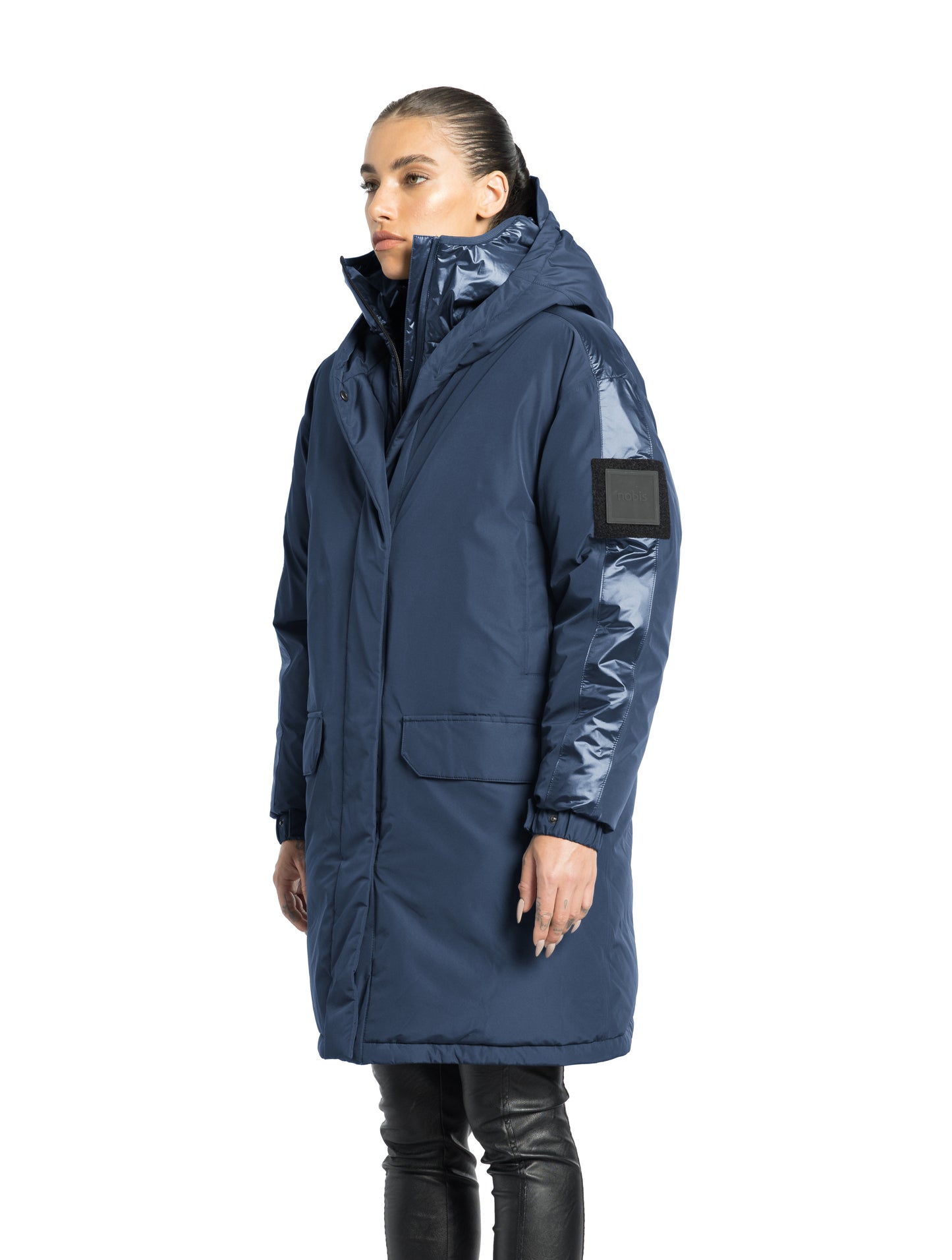 Slyn Women's Performance Parka in thigh length, premium 3-ply micro denier and cire technical nylon taffeta fabrication, Premium Canadian origin White Duck Down insulation, non-removable down-filled hood, inner hooded gilet, two-way centre-front zipper with magnetic closure wind flap, fleece-lined pockets at chest and waist, pit zipper vents, in Marine