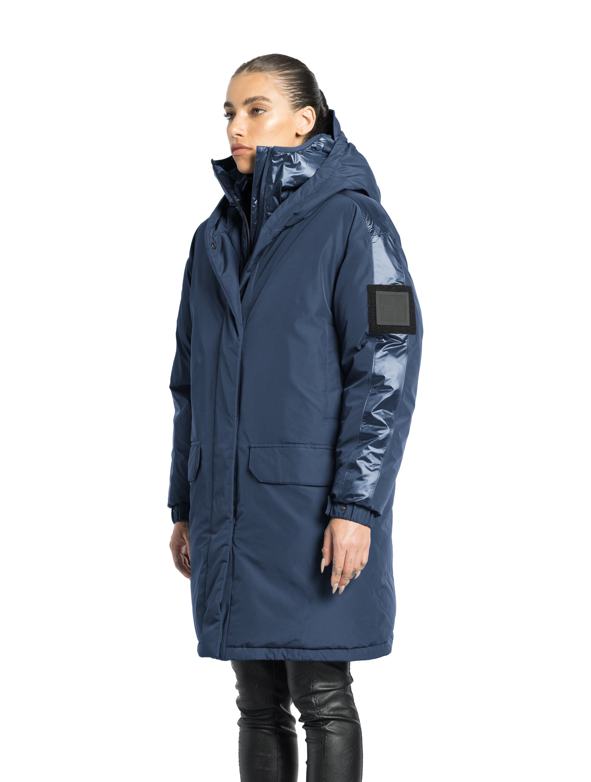 Slyn Women's Performance Parka in thigh length, premium 3-ply micro denier and cire technical nylon taffeta fabrication, Premium Canadian origin White Duck Down insulation, non-removable down-filled hood, inner hooded gilet, two-way centre-front zipper with magnetic closure wind flap, fleece-lined pockets at chest and waist, pit zipper vents, in Marine