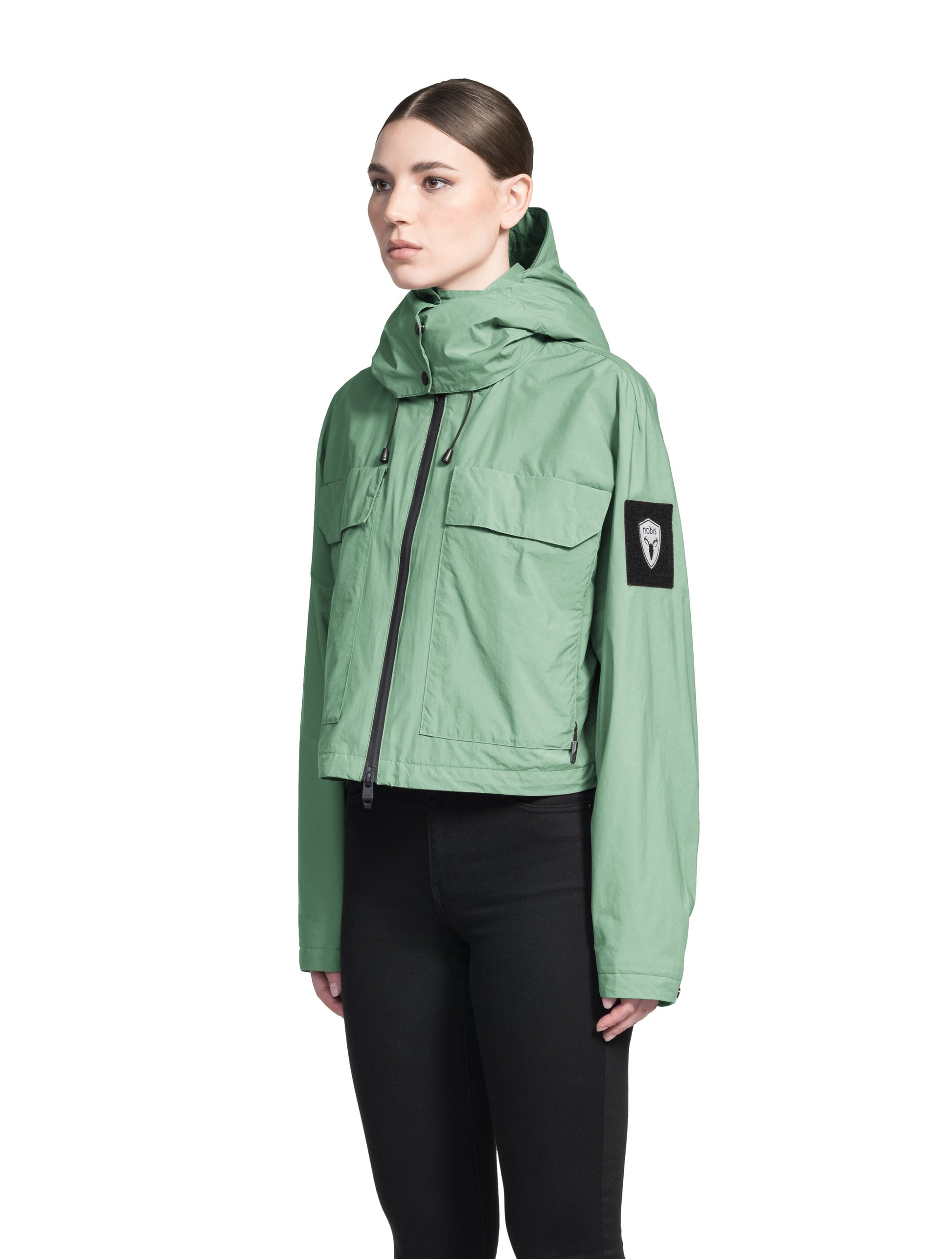 Viva Women's Performance Cropped Jacket in waist length, premium iridescent fabrication, removable hood with peak, adjustable hood draw cords and toggle, 2-way branded zipper at centre front, oversized magnetic closure flap pockets at chest with side entry, interior adjustable draw cord at hem, large interior zipper pocket, and adjustable snap cuffs, in Comfrey