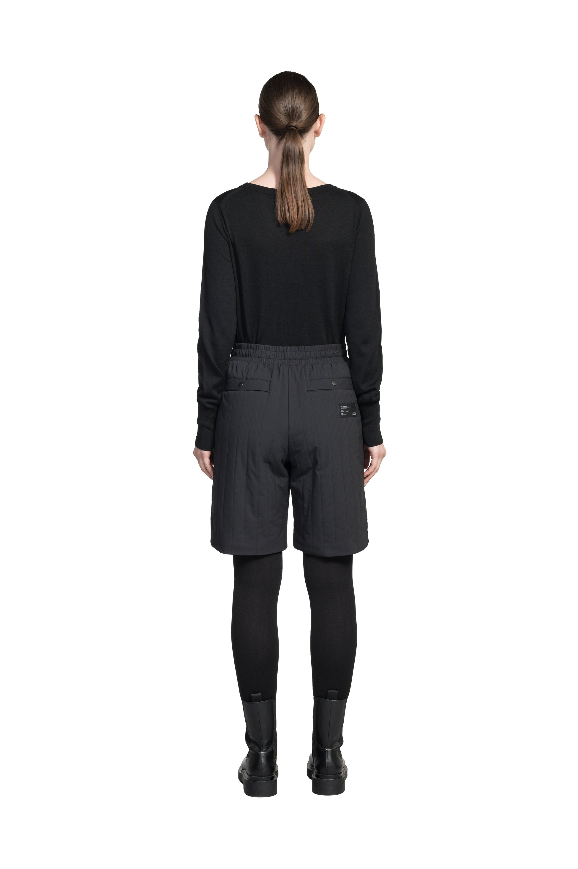 Kit Women's Quilted Shorts in knee length, premium stretch ripstop and contrast cire technical nylon taffeta fabrication, premium 4-way stretch, water resistant Primaloft Gold Insulation Active+, elasticized waistband with grosgrain ribbon drawstrings, hidden side seam toggles for rouching detail, snap closure side seam pockets at hips, and single welt snap button pockets at back, in Black