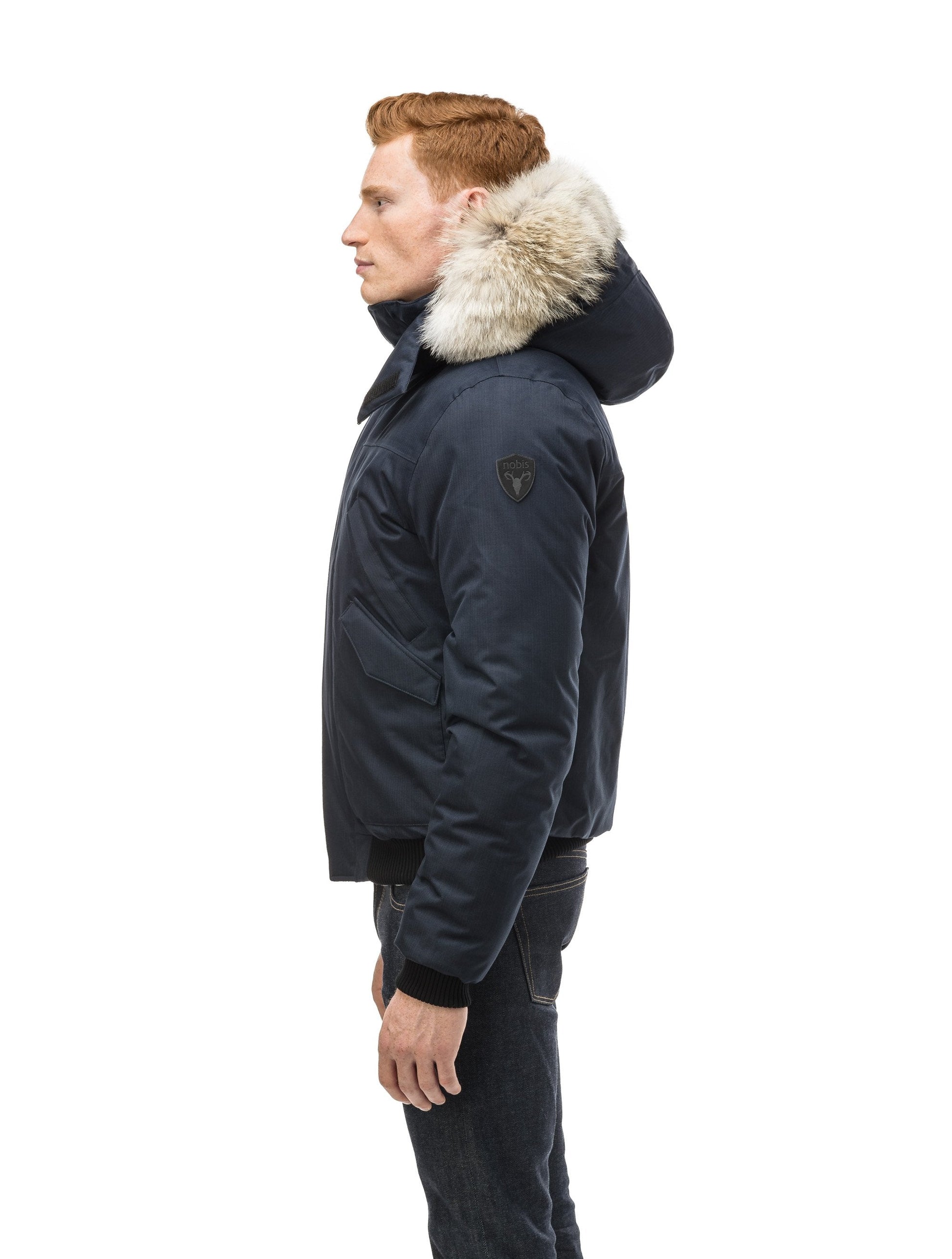 Men's classic down filled bomber jacket with a down filled hood that features a removable coyote fur trim and concealed moldable framing wire in Navy