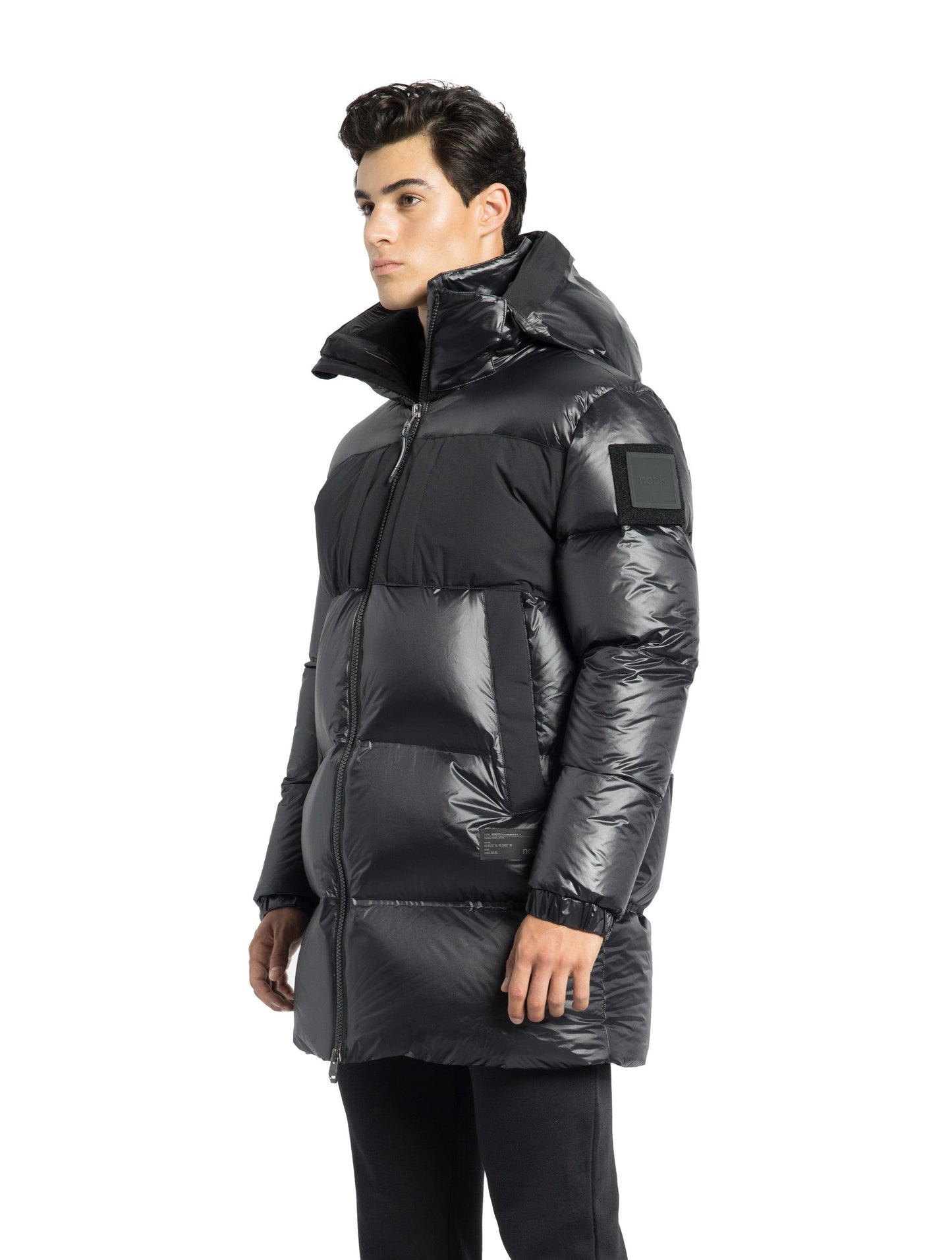 Neelix Men's Long Puffer Jacket in thigh length, premium cire technical nylon taffeta and stretch ripstop fabrication, Premium Canadian origin White Duck Down insulation, non-removable down-filled hood, two-way centre-front zipper, pit zipper vents, hidden chest zipper pockets, fleece-lined magnetic closure waist pockets, in Black